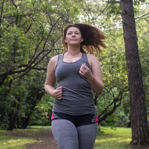 Woman jogging outdoors along a tree-lined path