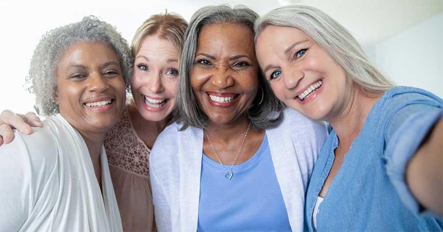 Group of four smiling women over 40