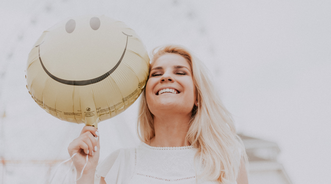 SMiling woman holding a smiley faced balloon - Libby for sexual health