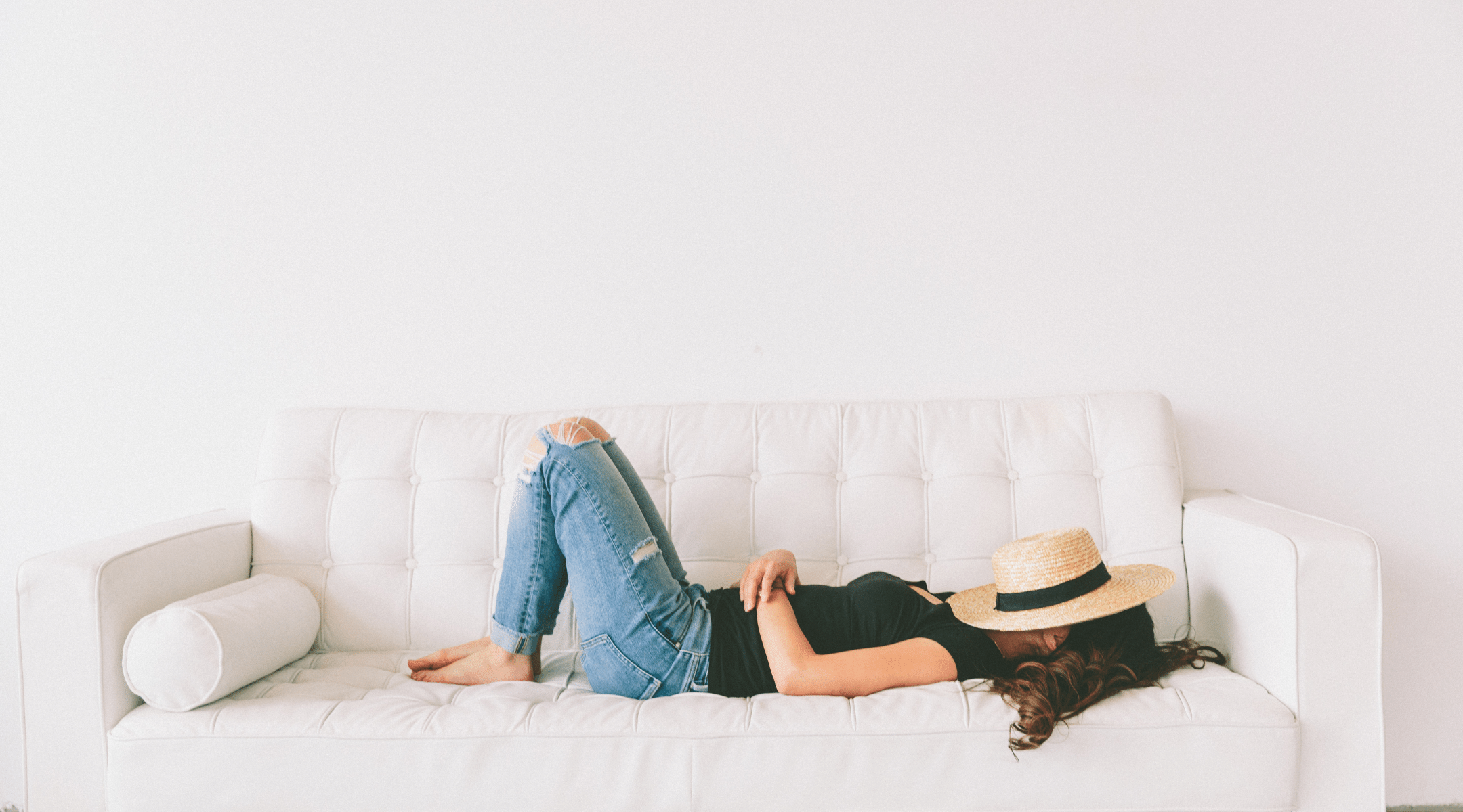 Woman laying on a sofa with a fedora over her face. Try to Relax